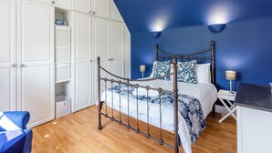 Ein Schlafzimmer mit Bett, Schrank, Nachttischen und einer blauen Wand.