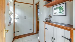 Un pasillo con una puerta de madera, un armario blanco con manijas negras y una obra de arte enmarcada en la pared.