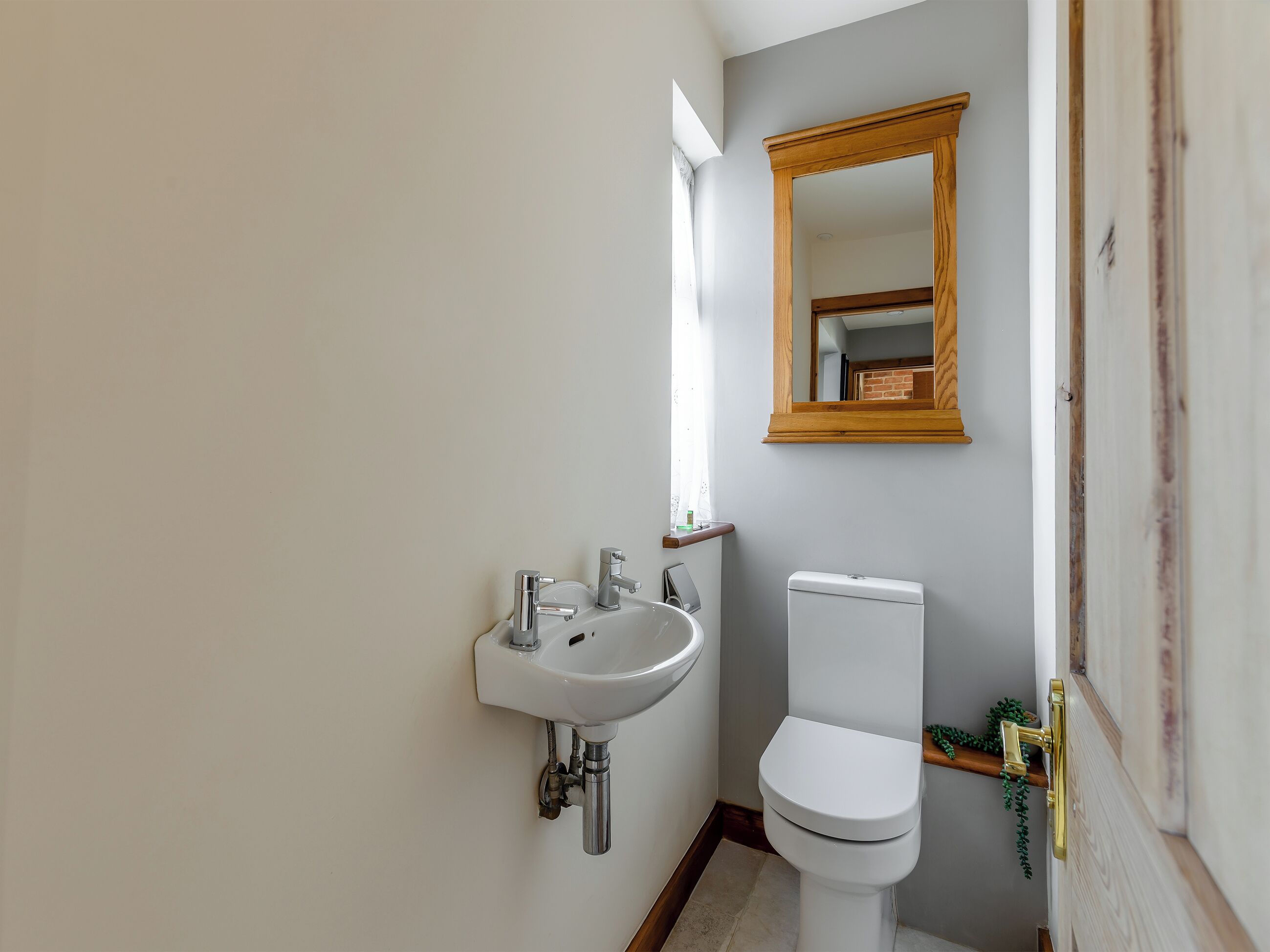 A bathroom with a white sink, a toilet, and a wooden-framed mirror.