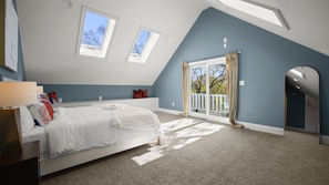 A bedroom with a bed, a nightstand, a window, and a door leading to a balcony.