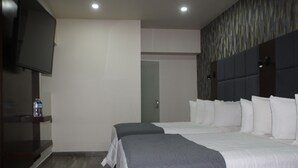 A hotel room with two beds, a flat-screen TV, and a wooden shelf with a bottle. - MISION 11 (Tijuana)