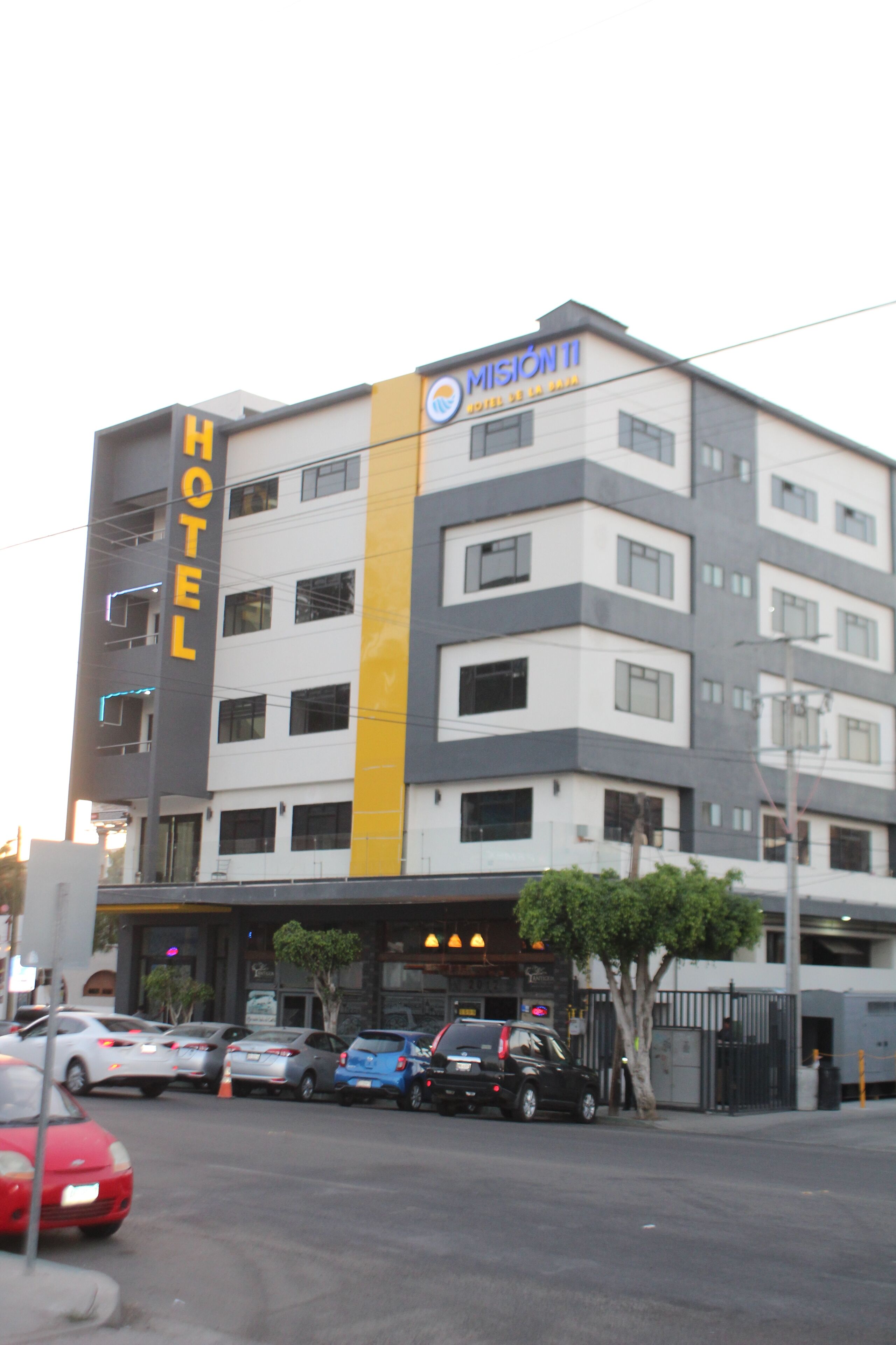 Un hotel de varios pisos con un llamativo letrero que dice 'HOTEL' en la fachada, con un diseño moderno y un toque amarillo.