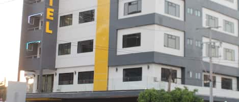 Un hotel de varios pisos con un llamativo letrero que dice 'HOTEL' en la fachada, con un diseño moderno y un toque amarillo.