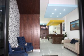Un área de recepción moderna con mostrador, zona de espera con sillones y mostrador de información.