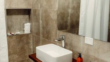 Un baño moderno con un lavamanos grande, un espejo y una zona de ducha.