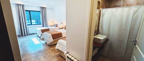Ein Hotelzimmer mit zwei Betten, einem Badezimmer mit Dusche und Blick nach außen.