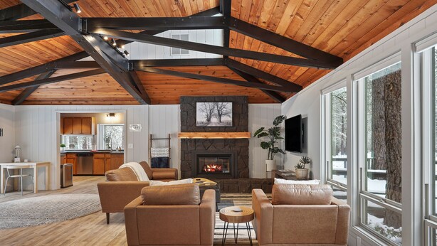 A spacious living area with a fireplace, wooden beams, and large windows. - 12 Quartz Mtn - Updated and Classy! Pickleball, SHARC, Fireplace, Backs to Sunriver Forest (Sunriver)