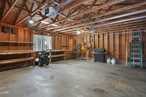 Exposed beams and concrete floor create a versatile space with a work area, large window, and storage options.