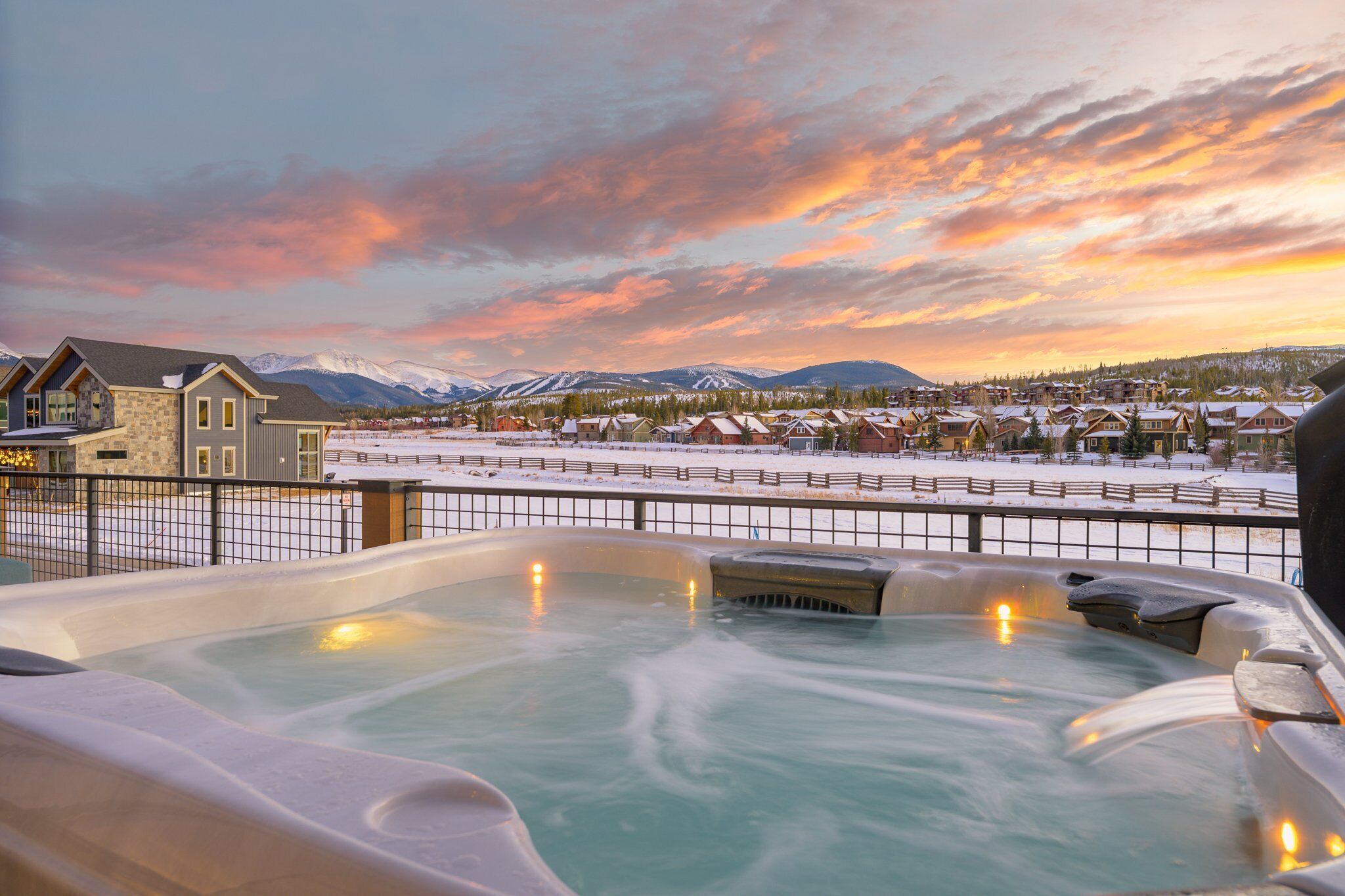 Un jacuzzi con vistas a un paisaje nevado y montañas al fondo.