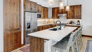 Eine moderne Küche mit Holzausstattung, Edelstahlgeräten und einer zentralen Kochinsel mit Barhocker.