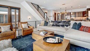 Ein geräumiger Wohnbereich mit einer großen Couch, einem Couchtisch und einer Treppe, die in eine obere Etage führt.