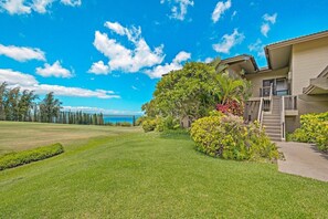 A modern house with a well-maintained lawn and a view of the ocean. - Panoramic Ocean Views - Rare Kapalua Ridge Villa (Lahaina)