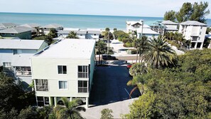 A coastal residential area with multiple two-story houses, a street, and a view of the ocean. - Welcome to Paradise Cove! - Steps From The Beach (Indian Shores)