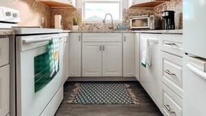 A modern kitchen with white cabinets, a built-in oven, a microwave, and a coffee maker. - Welcome to Paradise Cove! - Steps From The Beach (Indian Shores)