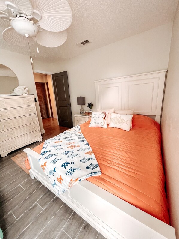 A bedroom with a bed, dresser, and a ceiling fan. - Welcome to Paradise Cove! - Steps From The Beach (Indian Shores)