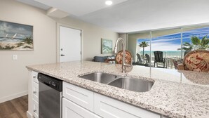 A kitchen with a granite countertop, stainless steel sink, and a dishwasher.