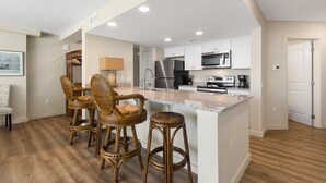 A modern kitchen with white cabinets, stainless steel appliances, and a central island.