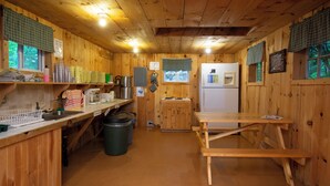 Cocina de cabaña de madera con una mesa de madera, un lavamanos y un refrigerador.
