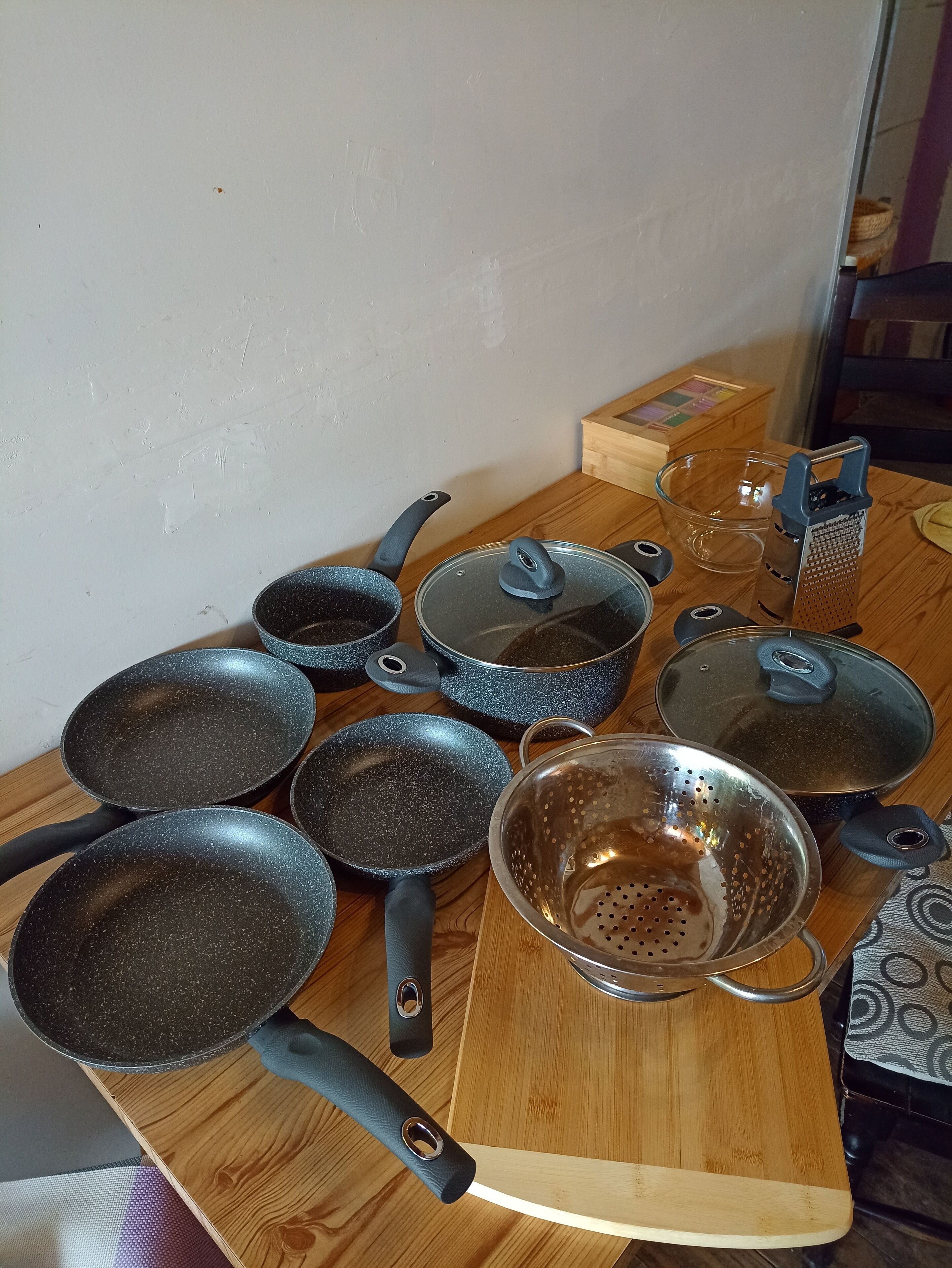 Un plan de travail de cuisine avec divers ustensiles, notamment des poêles, une passoire et une râpe.