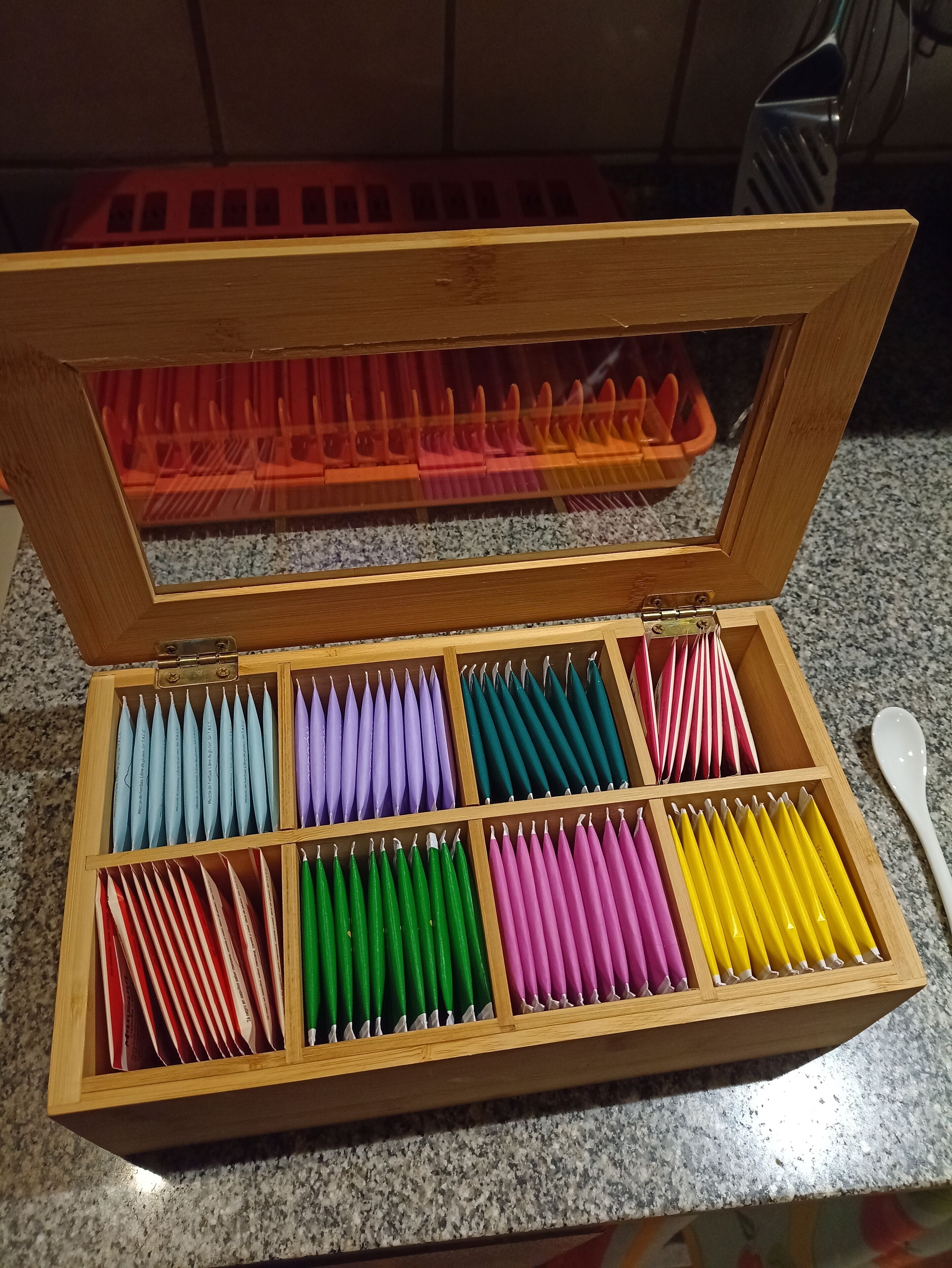Una caja de madera con compartimentos que contienen lápices de colores.