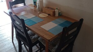 A wooden dining table with two chairs, a small decorative tree, a water bottle, and a box on the table.