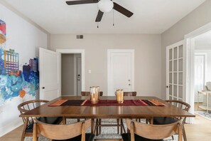 A dining room with a wooden table, six chairs, a ceiling fan, and a colorful abstract wall mural. - Newly Renovated 2BR Apartment w/ Free Parking in Downtown (Lexington)