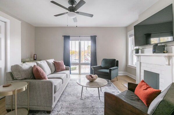 A living room with a sofa, armchair, coffee table, and a fireplace. - Newly Renovated 2BR Apartment w/ Free Parking in Downtown (Lexington)