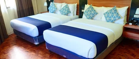 Two twin beds with matching blue and white bedding, wooden headboards, and patterned pillows.