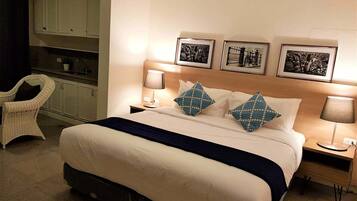 Een hotelkamer met een bed, twee nachtkastjes, een stoel en een kitchenette.