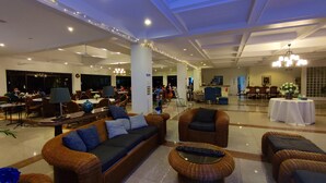 Un vestíbulo amplio con muebles de mimbre, un candelabro y un comedor al fondo.