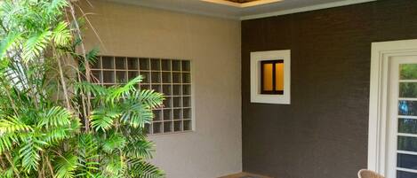 A spa area with a hot tub, a potted plant, and a window with blinds.