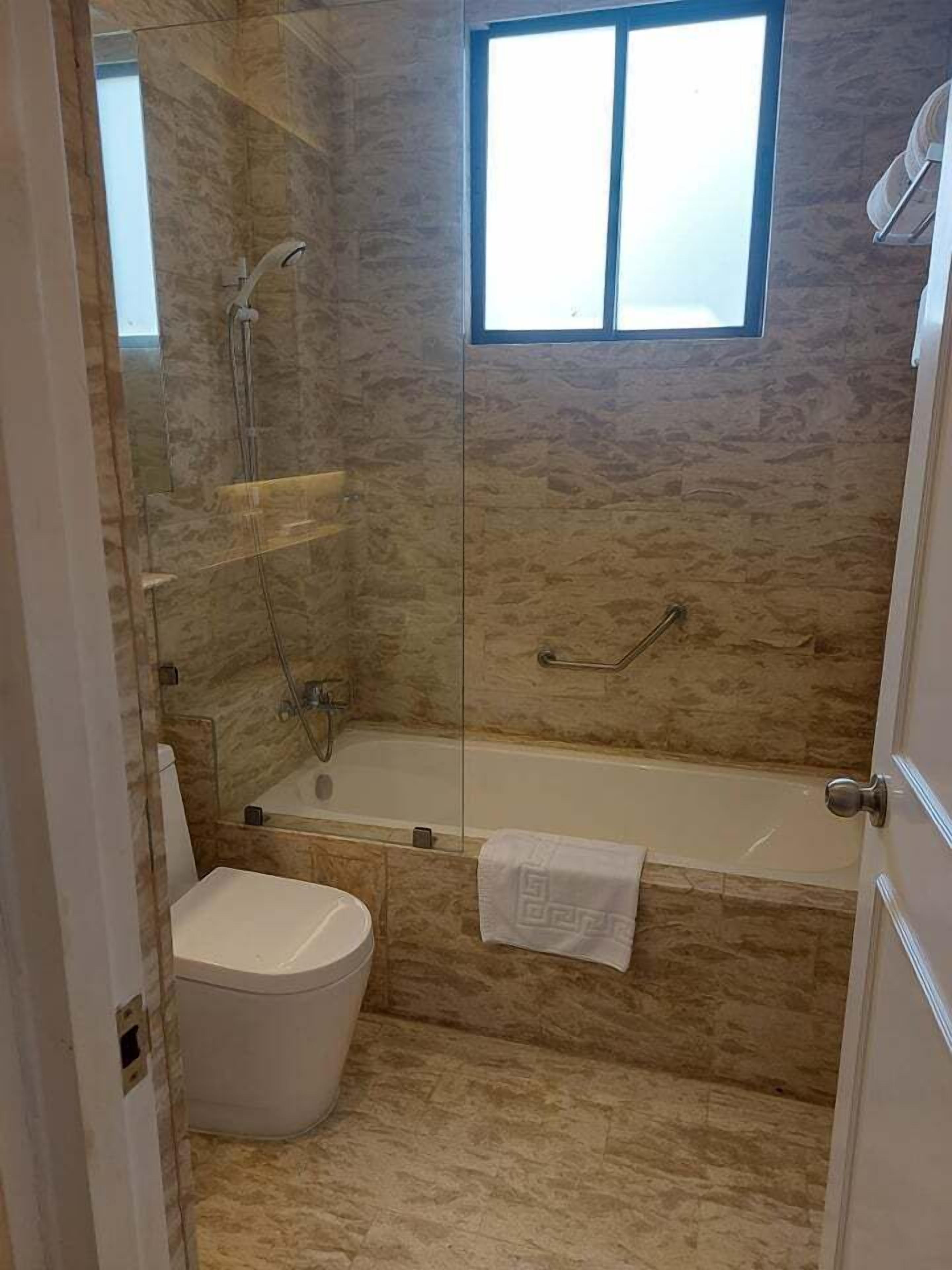 A bathroom with a glass-enclosed shower, a bathtub, and a toilet.