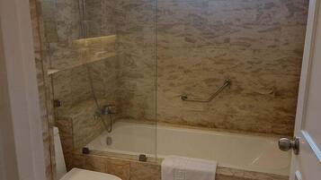 A bathroom with a glass-enclosed shower, a bathtub, and a toilet.
