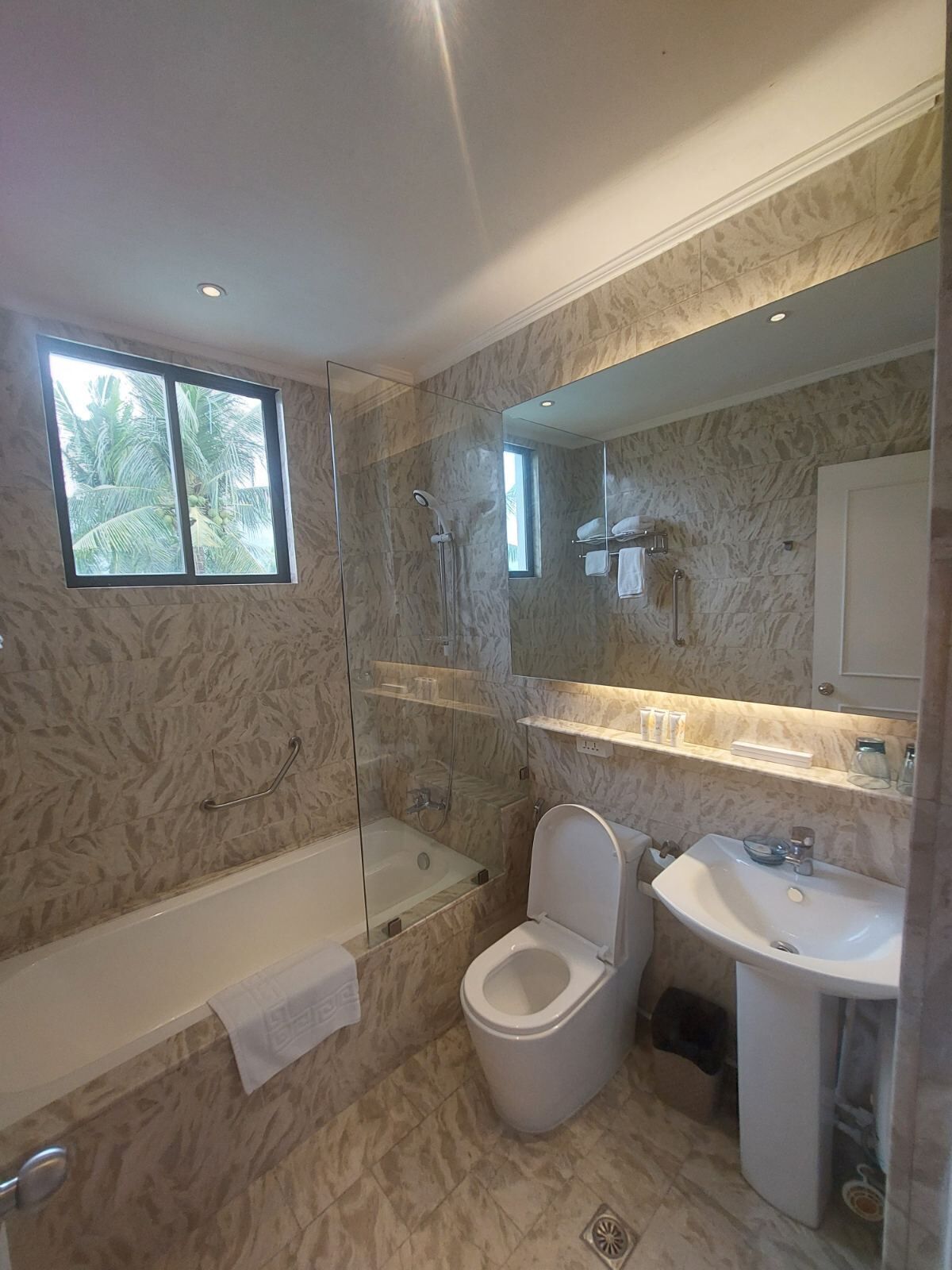 A modern bathroom with a glass-enclosed shower, a toilet, a sink, and a bathtub.