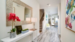 A hallway with a stone accent wall, a white console table with decorative items, a lamp, and a staircase leading to another room. - Exclusive Villa with Breathtaking Views, Orlando Villa 4226 (Orlando)