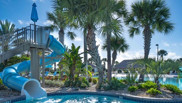 A swimming pool with a water slide, palm trees, and lounge chairs. - Exclusive Villa with Breathtaking Views, Orlando Villa 4226 (Orlando)