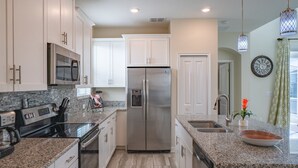 A modern kitchen with white cabinets, stainless steel appliances, granite countertops, and a built-in oven. - Exclusive Villa with Breathtaking Views, Orlando Villa 4226 (Orlando)
