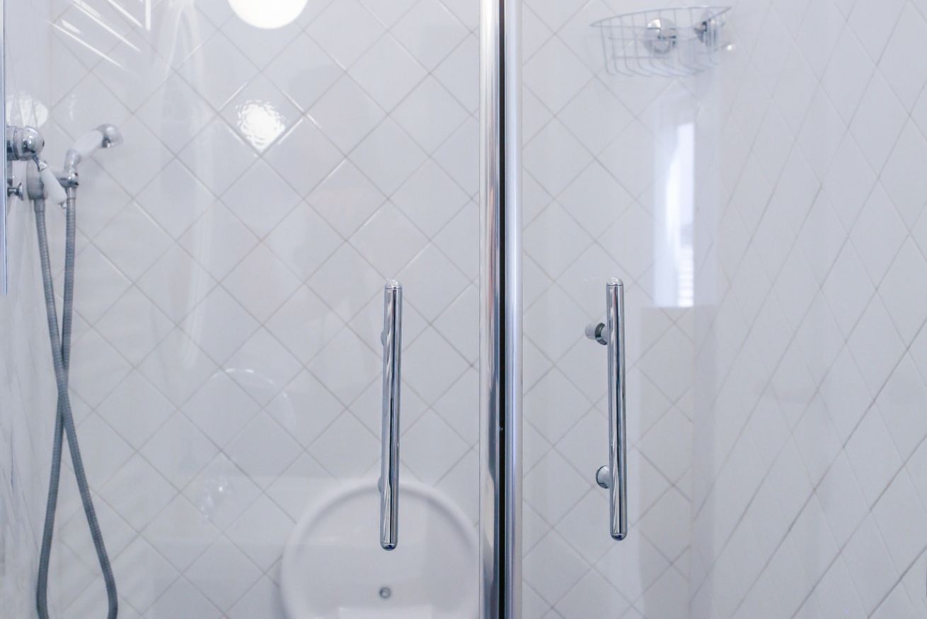 A glass-enclosed shower area with chrome fixtures and a tiled wall.