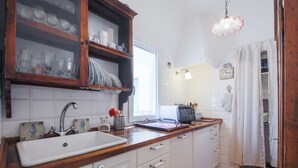 Eine Küche mit einer Holzausziehtheke, einem weißen Spülbecken und einem Schrank mit Glastüren.