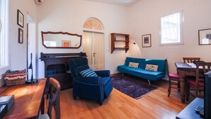 Ein Wohnzimmer mit Kamin, einer Couch, einem Esstisch und einem Klavier.