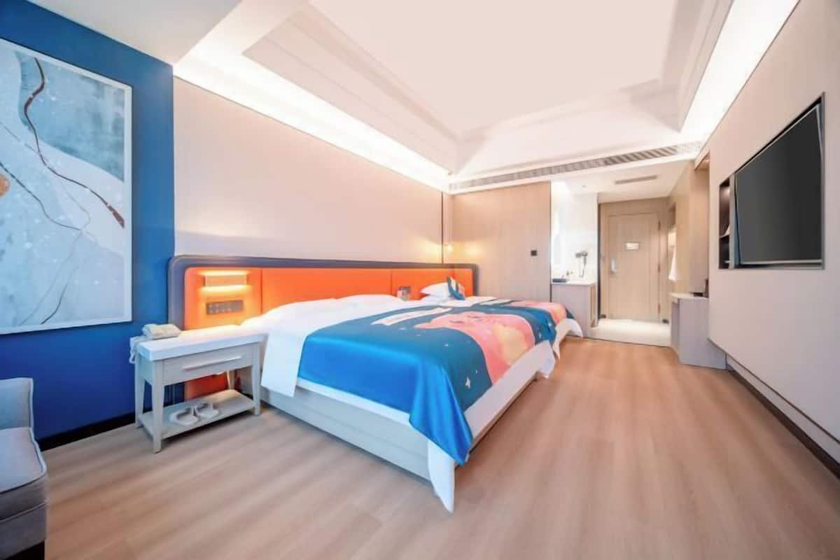 Une chambre d’hôtel moderne, équipée d’un lit, d’une table de chevet et d’une grande fenêtre.