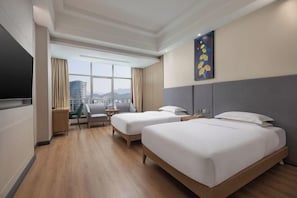 A hotel room with two beds, a TV, a desk, and a chair.