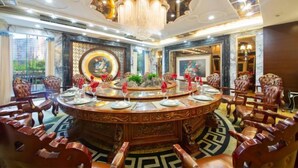 Uma sala de jantar luxuosa com uma mesa redonda, cadeiras elaboradas e um candelabro.