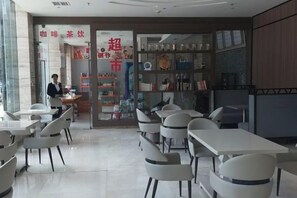 A cafe with tables and chairs, a counter with a menu, and shelves with various items. - Ramada Hotel Zhangjiajie (Tianmen Mountain Cable Car Station) (Zhangjiajie)
