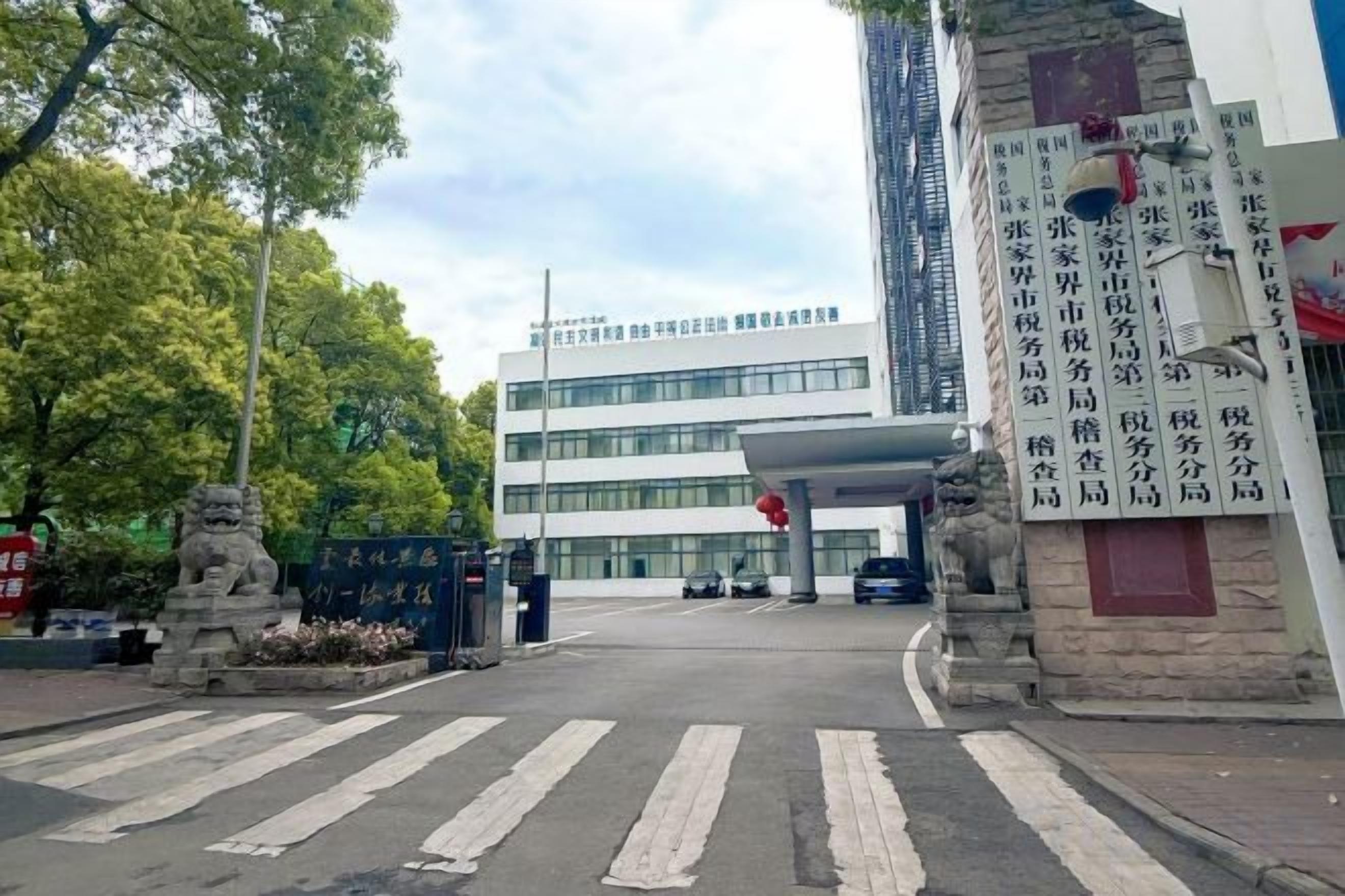A building entrance with a crosswalk, a statue, and a sign with text.