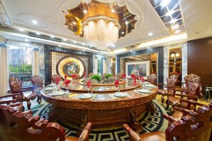 A luxurious dining area with a round table, ornate chairs, and a chandelier.