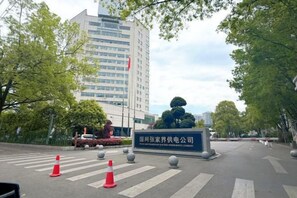 A street view with a building entrance, traffic cones, and a sign. - Ramada Hotel Zhangjiajie (Tianmen Mountain Cable Car Station) (Zhangjiajie)