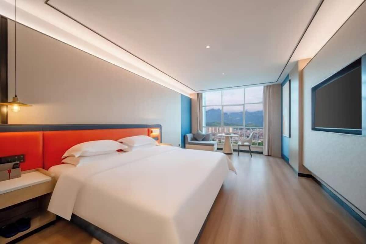 Une chambre d’hôtel moderne, dotée d’un grand lit, d’un bureau et offrant une vue sur la ville.