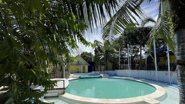 Una piscina de varios niveles con agua cristalina, rodeada de palmeras y un edificio al fondo.