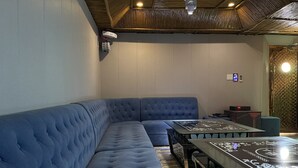 Un área de descanso moderna con un banco acolchado azul, una mesa de vidrio y un techo con diseño de madera.
